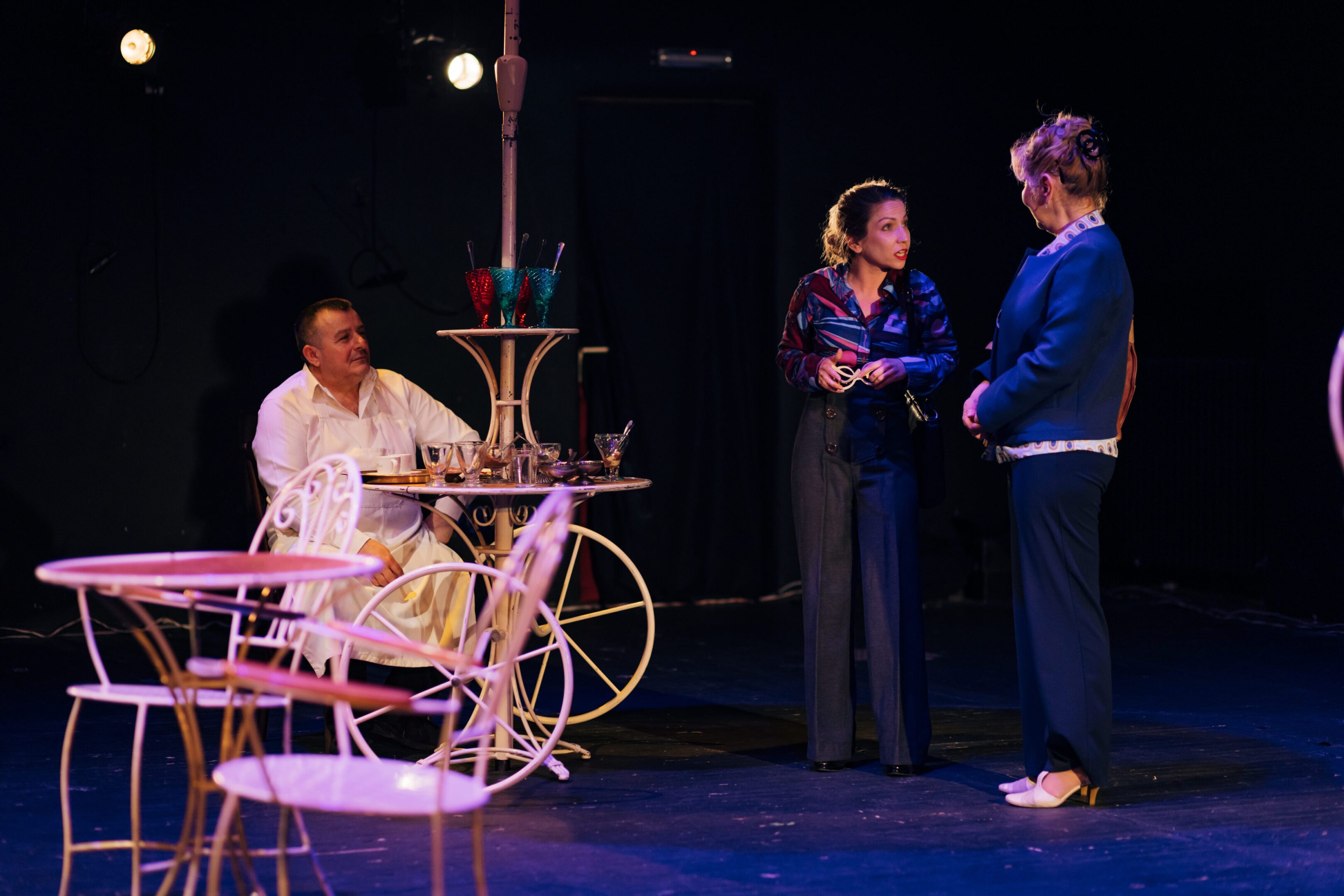 Three people conversing on a dimly lit stage.